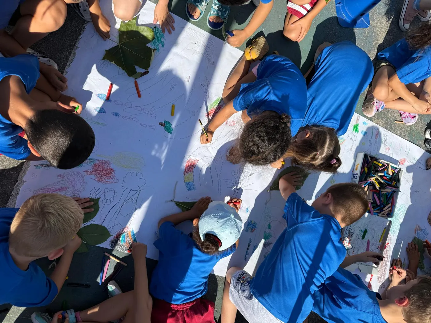 Niños del Campamento Urbano NSD dibujando juntos en el patio del colegio en Carabanchel